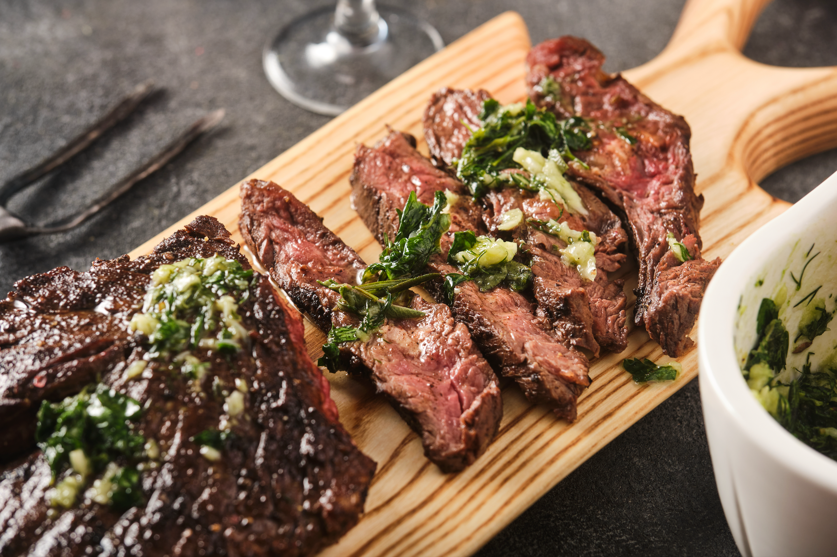 Cooked flank steak on a cutting board with a little sauce poured on top 